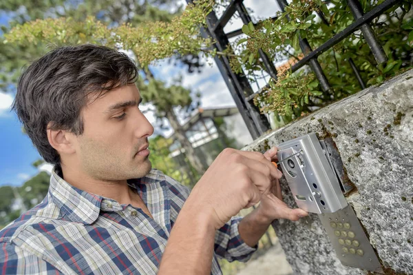 Hombre atornillando tapa de nuevo en el intercomunicador exterior —  Fotos de Stock