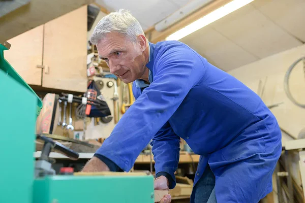 Älterer Schreiner arbeitet in seiner Werkstatt in Arbeitskleidung — Stockfoto