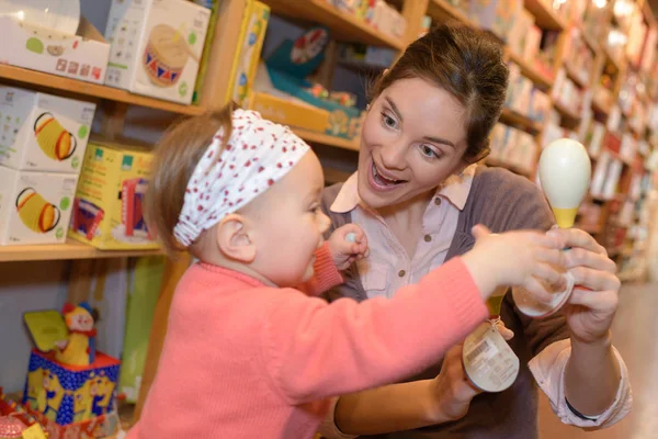 Madre feliz y divertido bebé de compras en la tienda de juguetes —  Fotos de Stock