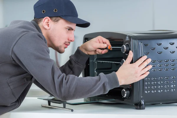 Trabajador que fija horno de microondas eléctrico — Foto de Stock