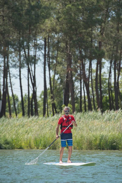 Człowiek cieszyć jazdą na jeziorze z paddleboard — Zdjęcie stockowe