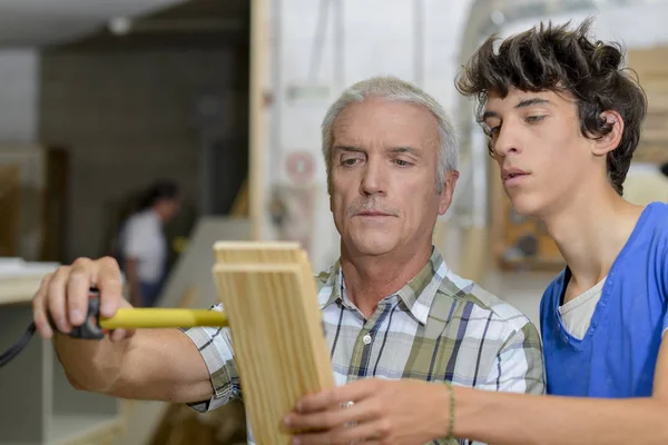 Carpintero con aprendiz, medida de madera —  Fotos de Stock