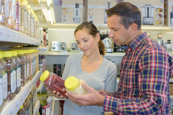 Man and lady comparing jars in store — Stock Photo, Image