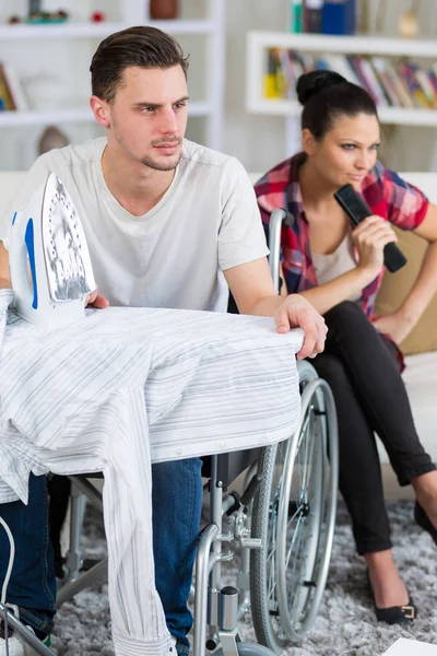 Schöner behinderter Mann im Rollstuhl vor dem Fernseher mit seiner Freundin — Stockfoto