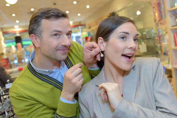 Vrouwelijke proberen oorbellen in de detailhandel opslaan — Stockfoto
