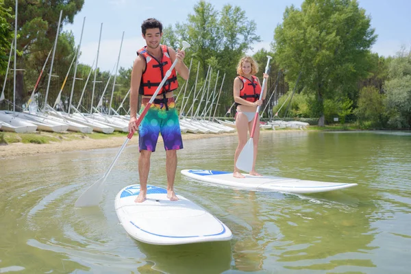 Man and woman standing on paddleboards Stock Photo