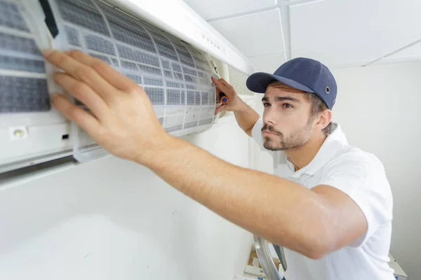 Porträt eines erwachsenen Technikers, der eine Klimaanlage repariert — Stockfoto