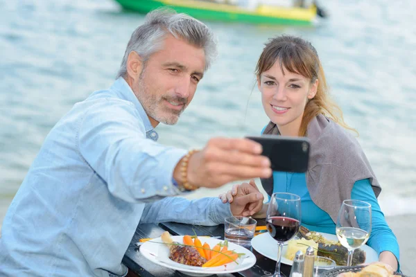 Hombre y mujer tomando fotografía autorretrato en terraza retaurante — Foto de Stock