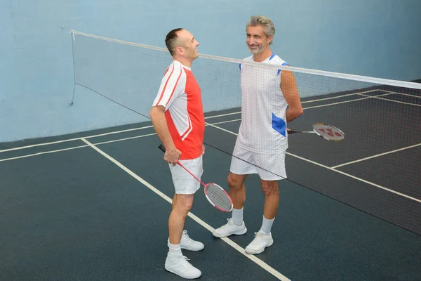 Mannen chatten over badminton net — Stockfoto