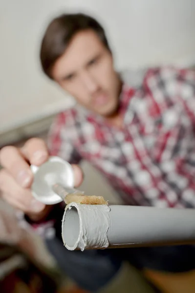 Mann klebt Kunststoffleim auf Ende des PVC-Rohres — Stockfoto