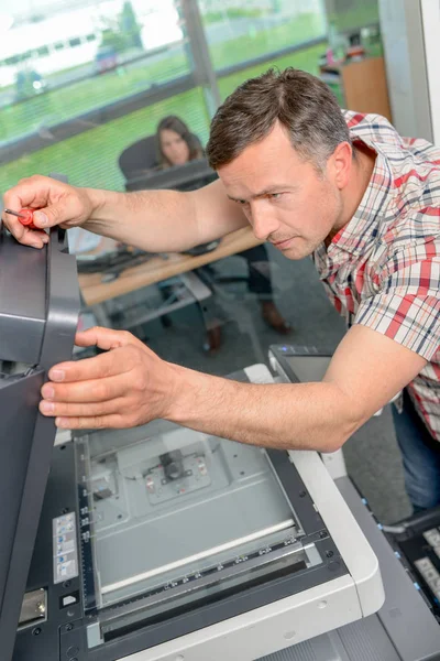 Человек пытается починить принтер — стоковое фото