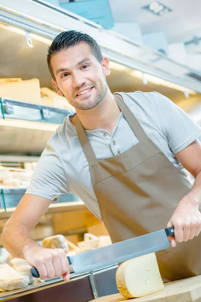 Man snijden kaas voor een klant — Stockfoto