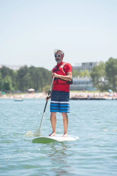 Homem desfrutando de um passeio no lago com paddleboard — Fotografia de Stock