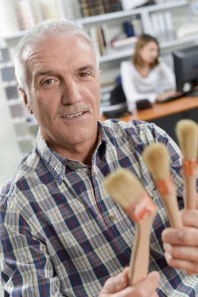 Trabajador de oficina sosteniendo pinceles — Foto de Stock