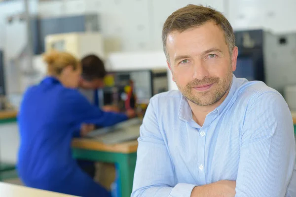 Portret van leraar, studenten in de achtergrond — Stockfoto