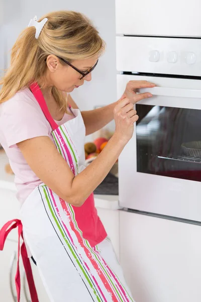 Домохозяйка мать устанавливает духовку для приготовления пищи — стоковое фото