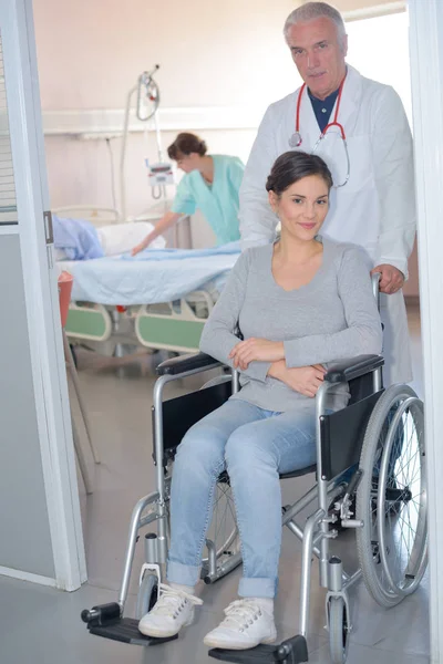 Doctor wheeling patient in wheelchair — Stock Photo, Image
