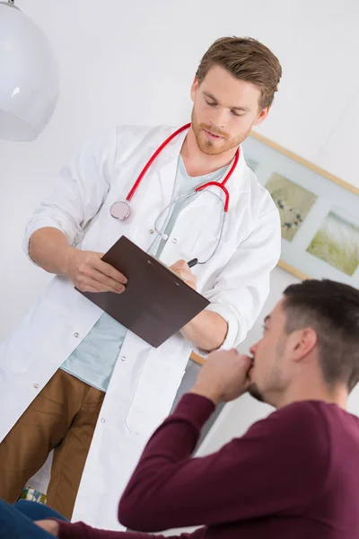 Médico questionando jovem paciente masculino — Fotografia de Stock