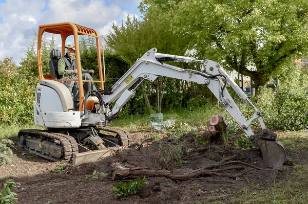 Hombre usando una excavadora en el jardín — Foto de Stock