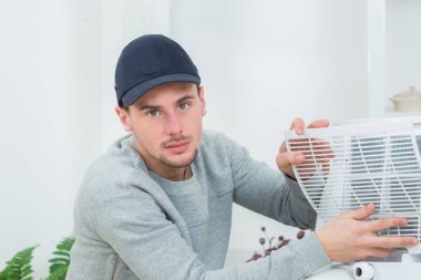 young technician installing air conditioning system indoors clipart