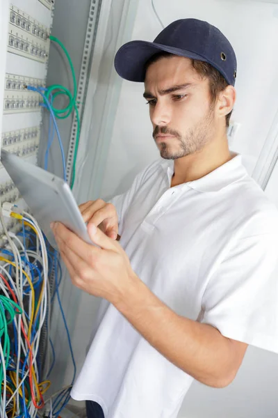 Eletricista focado aplicando procedimento de segurança enquanto trabalhava no painel elétrico — Fotografia de Stock