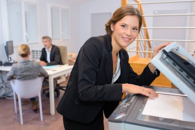 Portrait of businesswoman at photocopier clipart