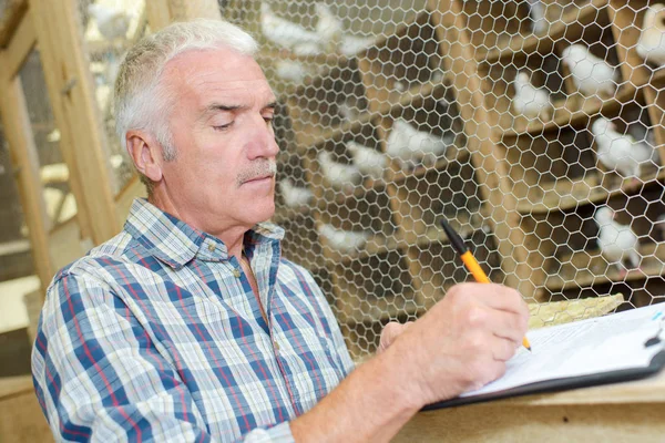 Hombre en el gallinero de palomas escribiendo en clipbaord —  Fotos de Stock