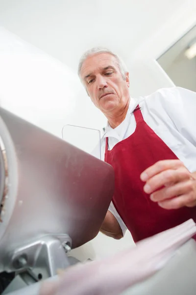 Butcher using a slicer — Stock Photo, Image