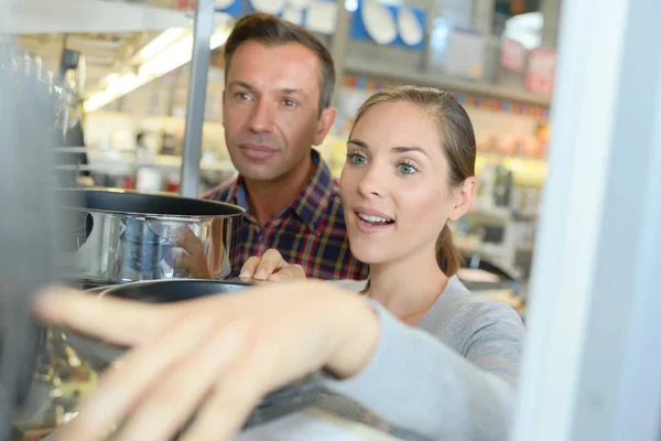 Man och kvinna att välja kastruller i butik — Stockfoto