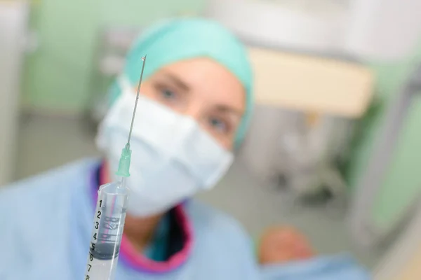 Крупный план шприца, удерживаемого медсестрой в маске — стоковое фото