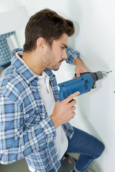 Constructor masculino perforando agujeros en la pared en el sitio de construcción — Foto de Stock