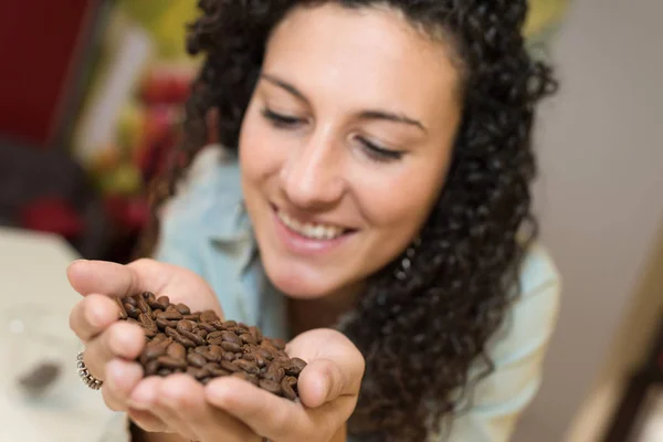 Jeune femme tenant quelques grains de café dans sa main — Photo