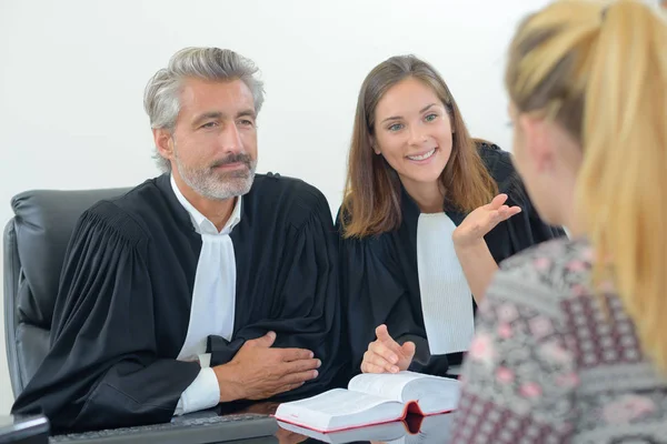 Юристы в халатах разговаривают с клиентом — стоковое фото