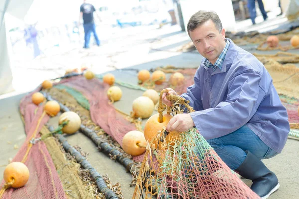 Homem que organiza redes de pesca — Fotografia de Stock