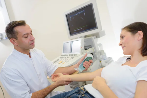 Médico que se prepara para digitalizar o braço do paciente — Fotografia de Stock