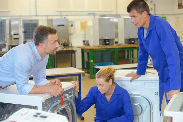 Apprentices looking at washing machines — Stock Photo, Image