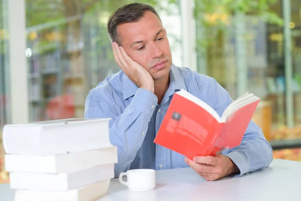 Homem leitura livro, olhando entediado — Fotografia de Stock