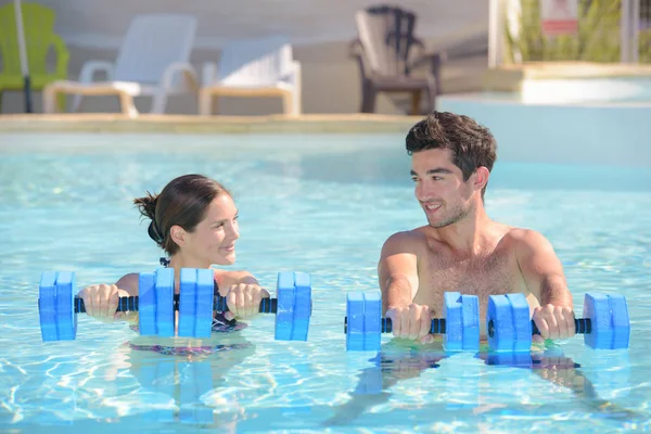 Homme dans la femme dans la piscine tenant des flotteurs — Photo