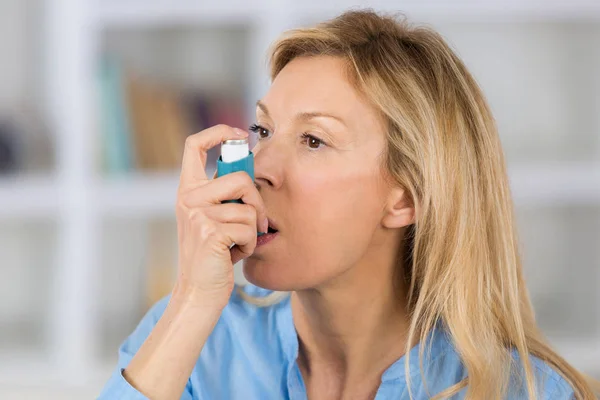 Κοντινό πλάνο γυναίκα τη συσκευή εισπνοής άσθμα χρήση στο σαλόνι- — Φωτογραφία Αρχείου