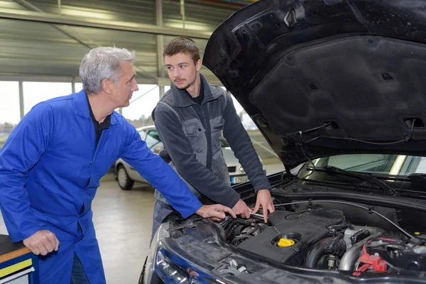 Estudiante con instructor reparando un coche durante el aprendizaje — Foto de Stock