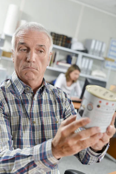 Hombre confundido sosteniendo una lata de pintura — Foto de Stock