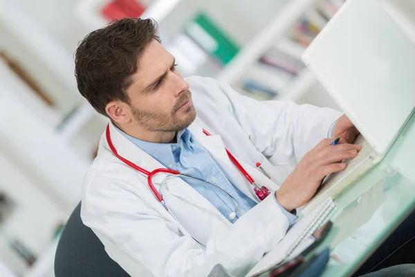 Schöner junger Arzt bei der Arbeit in seinem Büro — Stockfoto