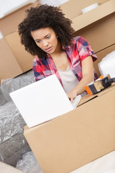 Mujer sentada en el suelo cerca de una caja con portátil — Foto de Stock