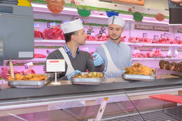 Metzger steht im Supermarkt hinter Theke — Stockfoto