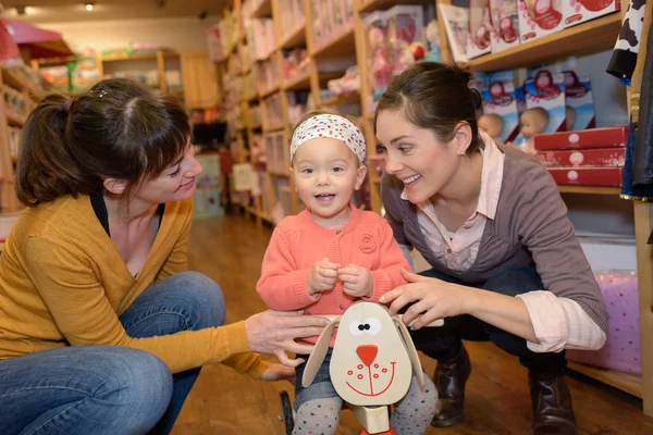 Mãe e filha com vendedor atraente na loja de brinquedos — Fotografia de Stock