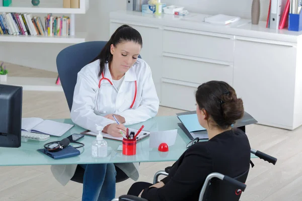 Médico mulher falando com seu paciente em uma cadeira de rodas — Fotografia de Stock