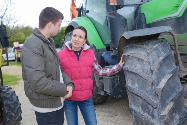 Atraente mulher vendendo novo trator para iniciante agricultor — Fotografia de Stock