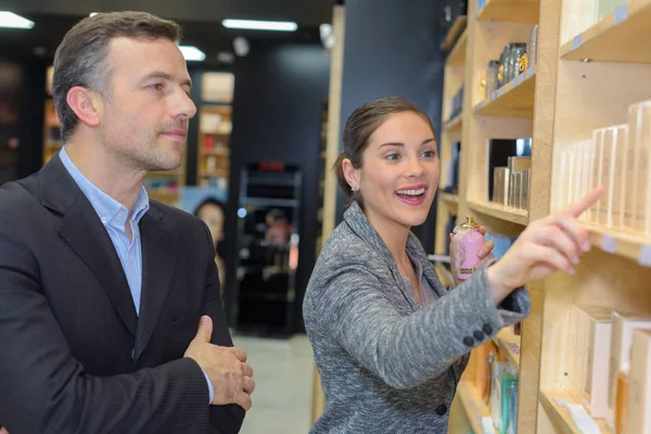 Beautiful saleswoman showing beauty products to male customer — Stock Photo, Image