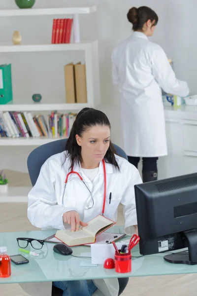 Läkare som arbetar på kontoret med sjuksköterska i bakgrunden — Stockfoto