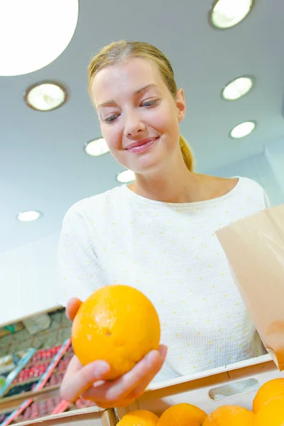 Senhora escolhendo laranjas e corredor — Fotografia de Stock